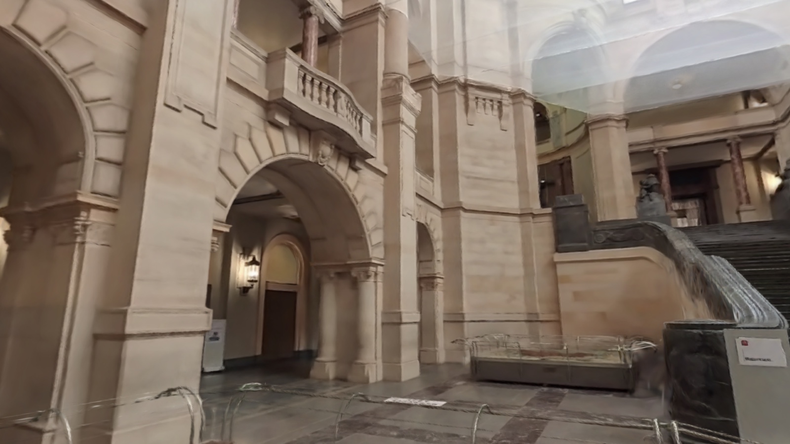 The same 3D scene, framed from the side across the colonnade toward the staircase